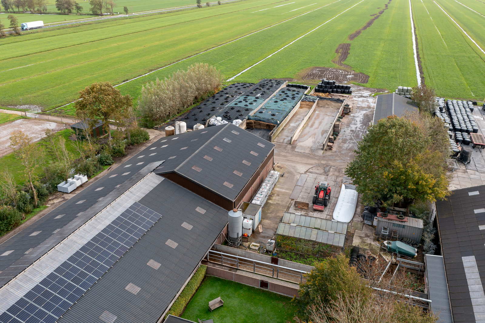 Luchtfoto van een agrarisch bedrijf met stallen, zonnepanelen en erf
