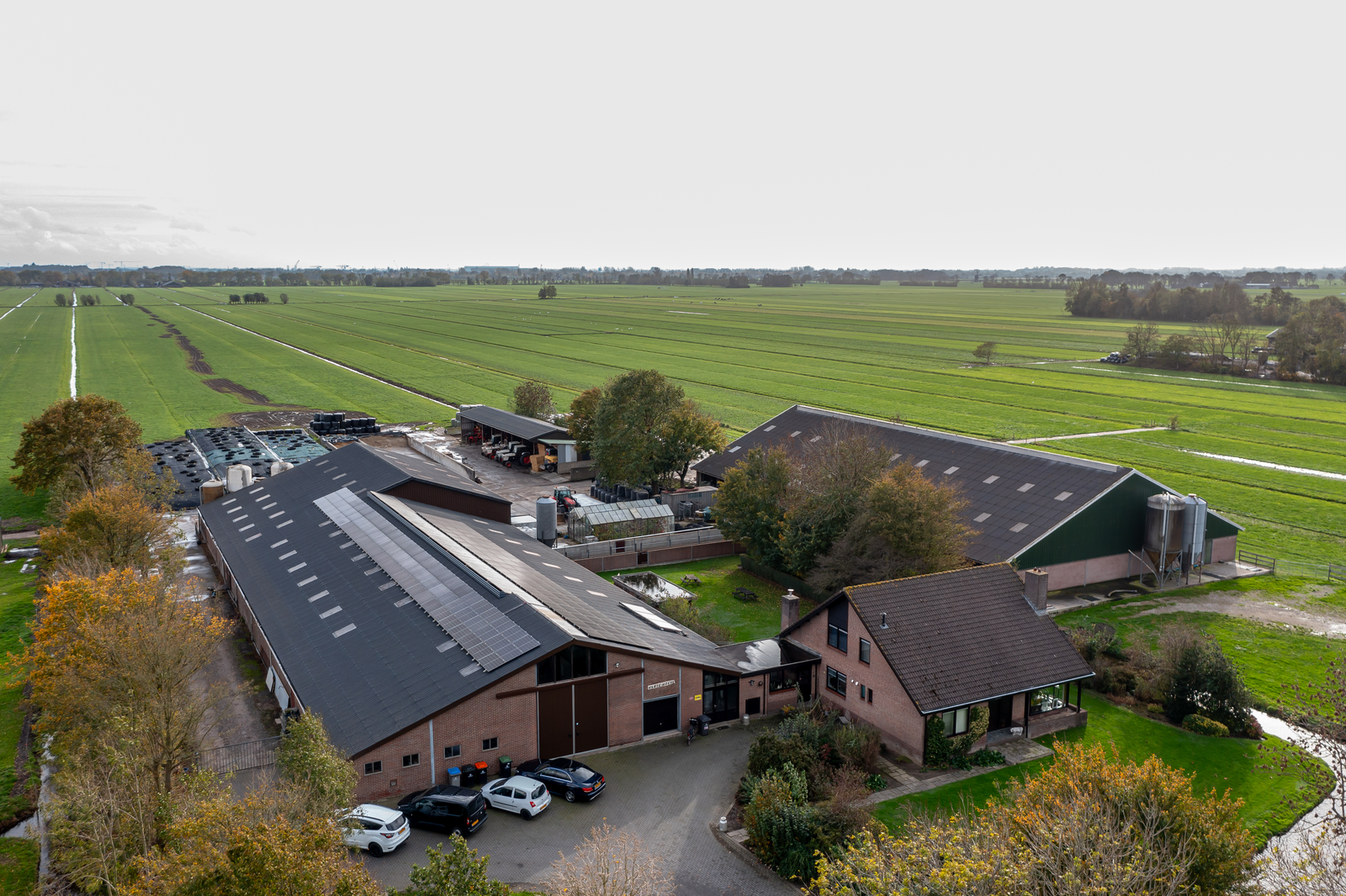 Luchtfoto van een melkveebedrijf met woonhuis, stallen en weilanden in de Alblasserwaard