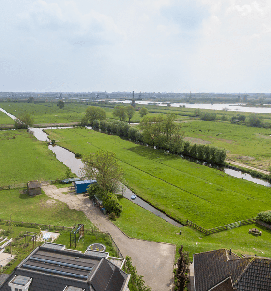 Luchtfoto van de polder in de Alblasserwaard met sloten, weilanden en molens aan de horizon