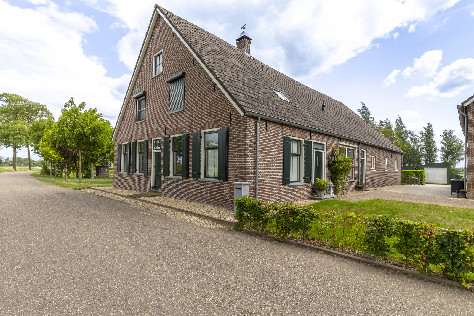 Karakteristieke boerderijwoning met groene luiken aan een landelijke weg in de Alblasserwaard