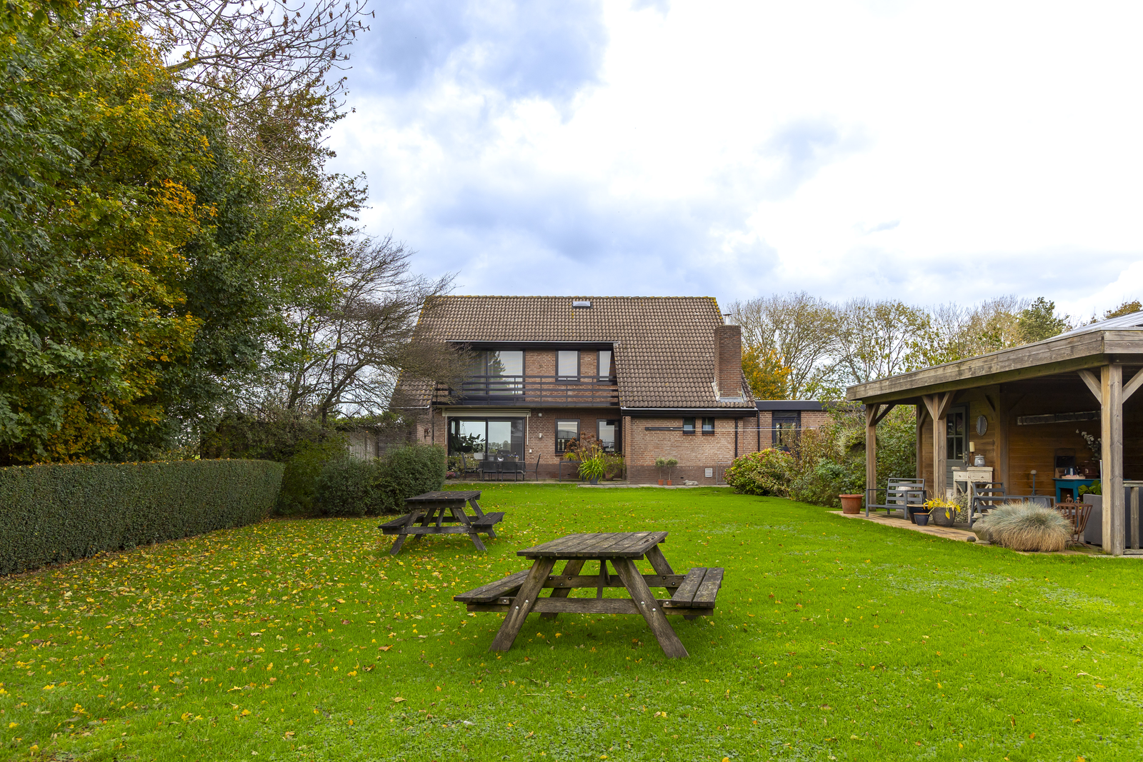 Achtertuin met picknicktafels en overkapping bij een vrijstaande woning